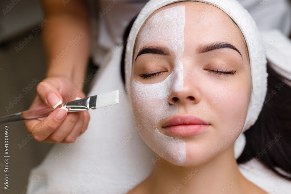 Wall mural close-up shot of a woman getting facial treatment with clay mask. cosmetology and spa