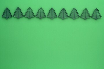 Christmas composition from little plastic pine trees on green background with copy space for text. Holidays, winter and celebration concept. Greeting card, poster sale, banner. Flat lay, top view
