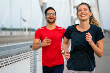 Early morning workout. Happy couple running across the bridge. Living healthy lifestyle.