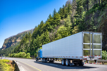 Classic blue American bonnet big rig semi truck transporting cargo in refrigerator semi trailer...