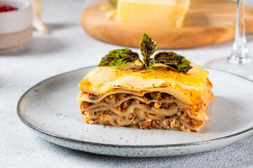 Piece of tasty hot lasagna on light background. Traditional italian lasagna. Italian food. Close up lasagna. Bolognese sauce. Bechamel sauce. Still life of food. Homemade meat lasagna