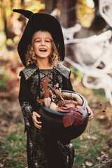 Beautiful girl witch. little girl in which costume celebrate Halloween outdoor and have fun. Kids...
