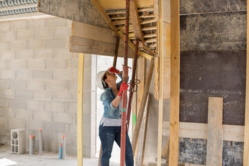 Fototapeta premium woman works on the carpenter of a house under construction