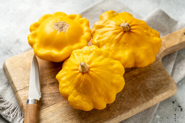 Yellow patisson in a basket on a light gray kitchen table close-up. Autumn harvest of bush pumpkin on a culinary background