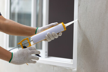 Construction worker using silicone sealant caulk the outside window frame. - 531010994