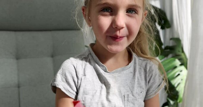 Little girl hides behind a rainbow fan peeks out with a smile at home