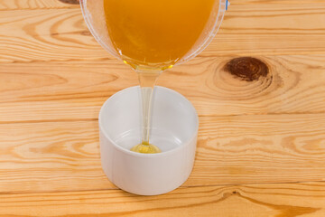 Fresh honey flowing in to cup on a rustic table