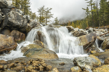 View of a mountain waterfall in the misty autumn forest. The beauty of wildlife