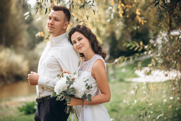 Beautiful happy couple married man and woman with a bouquet of flowers, portrait in nature