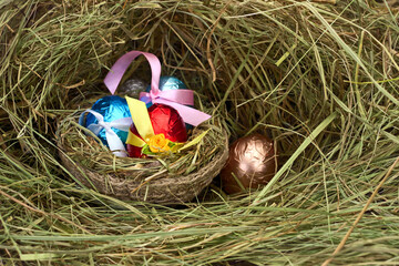Easter eggs in a nest of hay on wooden table