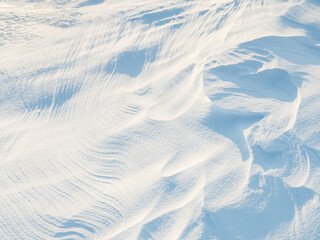 Snow texture. Wind sculpted patterns on snow surface. Wind in the tundra and in the mountains on the surface of the snow sculpts patterns and ridges (sastrugi). Arctic, Polar region. Winter background