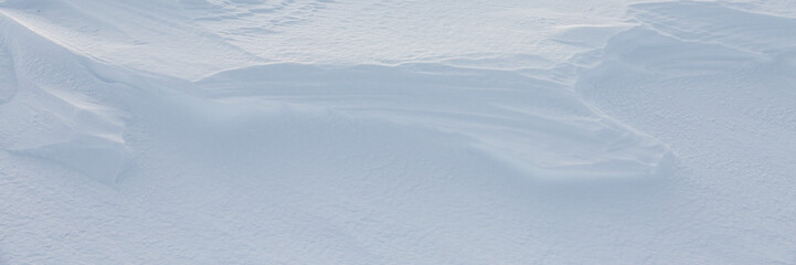 Beautiful winter background with snowy ground. Natural snow texture. Wind sculpted patterns on snow surface. Arctic, Polar region.