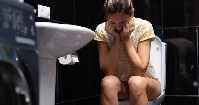 Woman is nervous suffers from diarrhea and sits in toilet