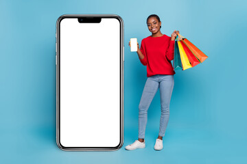 Full size photo of cool young lady near promo show telephone shopping wear shirt jeans shoes isolated on blue background
