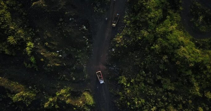 Aerial top down shot of trucks transporting sand of sand mine between destroyed rainforest