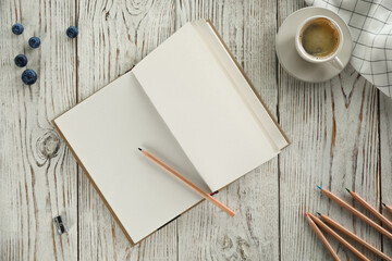 Flat lay composition with open notebook and cup of coffee on white wooden table