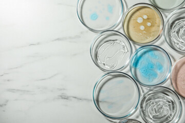 Petri dishes with liquids on white marble table, flat lay. Space for text