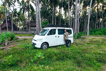 tourist with white camper van parked in a green field surrounded by trees in Bali Indonesia