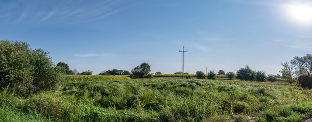 droga elektryczna na środku łąki, krajobraz w rejonie zachodniej polski zielone drzewa błękitne niebo	
