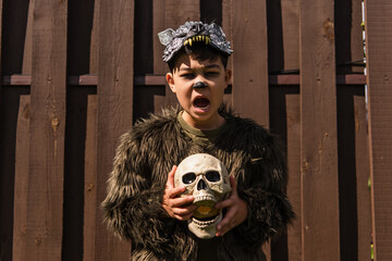 asian kid in werewolf costume growling and holding skull while looking at camera