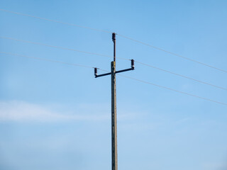 linia elektryczna idąca drogą polną, błękit nieba lekko pochmurna pogoda w tle, pora letnia	