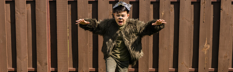 asian boy in werewolf halloween costume running and growling in backyard, banner