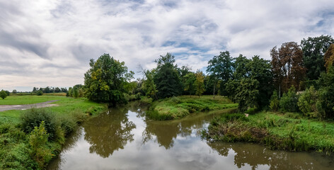 krajobraz rzeki Osobłogi w zachodniej Polsce w jasnych zielono niebieskich barwach i lekko pochmurnej pogodzie - obrazy, fototapety, plakaty