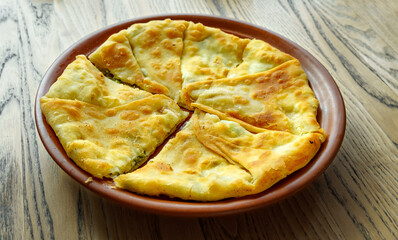 One placinda on a wooden table. Flour products of Moldovan cuisine include various fried pies with stuffing, cottage cheese or potatoes, cabbage, etc.