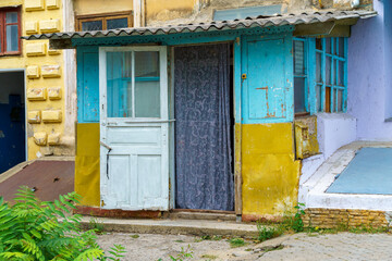 Fototapeta na wymiar the entrance to an old house, weathered paint on the walls, an open wooden door with a curtain, the first floor of a city house, a view from the street