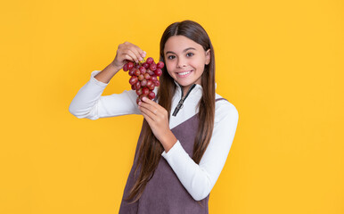glad child hold healthy grapes fruit on yellow background