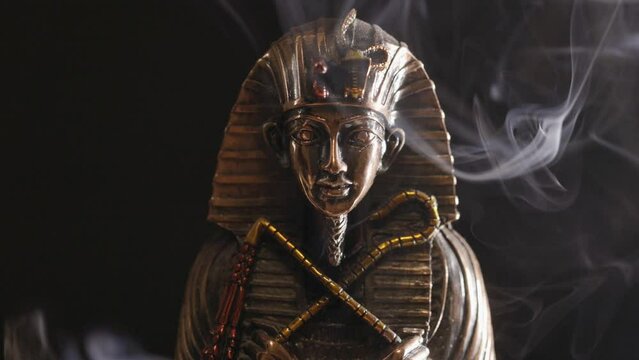 golden statue of the pharaoh in smoke on a black background