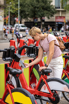 Red rental bikes Bicing on the parking station. Tourist woman use red bicycles with app. Barcelona, Spain - September 14, 2022
