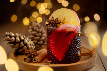 Red mulled wine with spices, orange and apple on wooden background. Close up