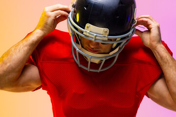 Caucasian male american football player wearing helmet with neon yellow and purple lighting