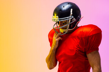 Caucasian male american football player wearing helmet with neon yellow and purple lighting