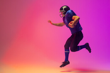 Fototapeta na wymiar Caucasian male american football player holding ball with neon pink lighting