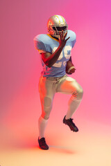 African american male american football player holding ball with neon pink lighting © WavebreakMediaMicro