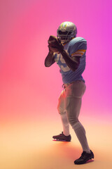 African american male american football player holding ball with neon pink lighting © WavebreakMediaMicro