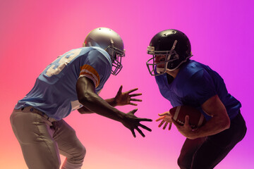 Fototapeta na wymiar Diverse male american football players holding ball with neon pink lighting