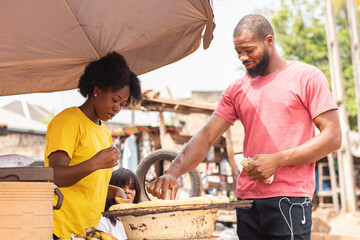 people buying roasted plantain from a roadside seller © Confidence