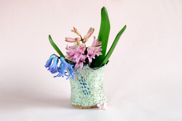 Vase with hyacinths on a pale pink background. Selective focus, natural light