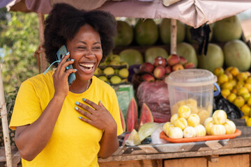 african lady in a market making a phone call excitedly