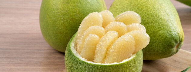 Fresh pomelo fruit on wooden table background.