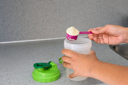 A woman on diet preparing breakfast drink making liquid meal from plant base protein Pea protein powdering the kitchen, closeup