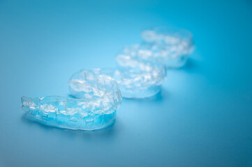 Invisible aligners on a blue background with copy space. Plastic braces for teeth alignment