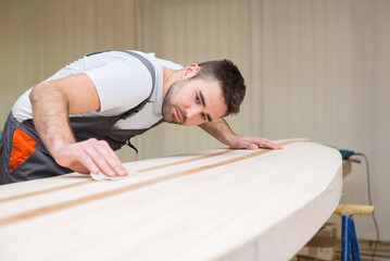 Young carpenter making wooden boat of his own design in his workshop