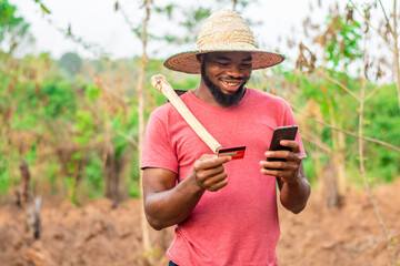 african farmer using his phone and credit card