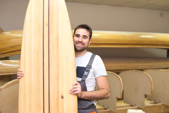 Young carpenter making surfboard of his own design in his workshop - Powered by Adobe