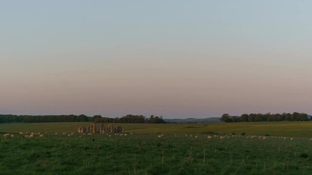 Day to night transition over english landscape with Stonehenge and sheeps moving around, England, United Kingdom
