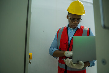 Engineer checking the electrical system with panel in control or server room.